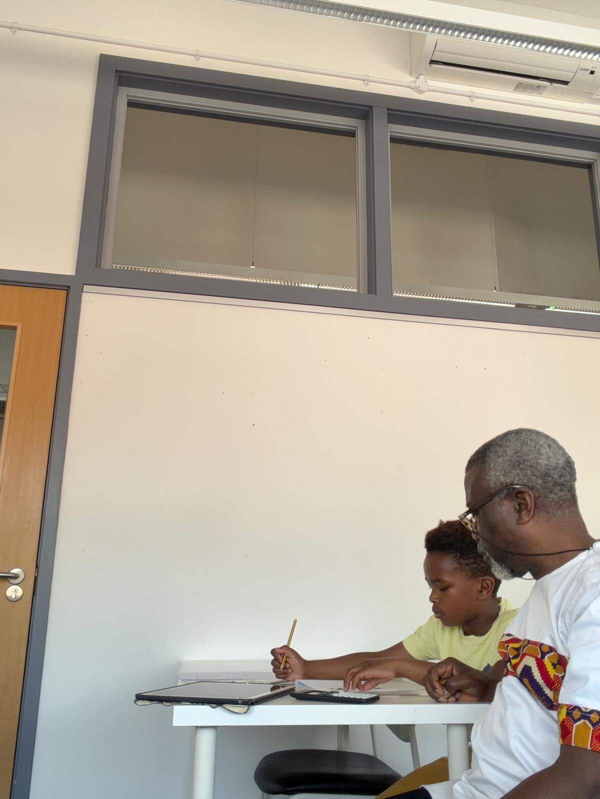 Sylvester Peprah working through a problem alongside a young student writing in his notebook